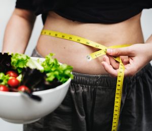 Woman with tape measure and salad